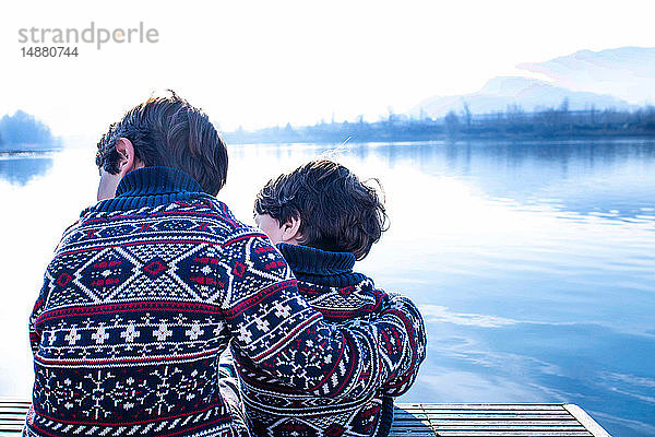 Junge und kleiner Bruder im passenden Pullover am Pier sitzend,  Comer See,  Lecco,  Lombardei,  Italien