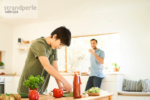 Junge bereitet Essen an der Küchentheke zu,  Vater schaut zu