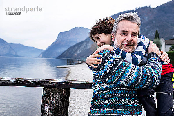 Junge und Vater umarmen sich am Pier des Comer Sees,  Comer See,  Onno,  Lombardei,  Italien