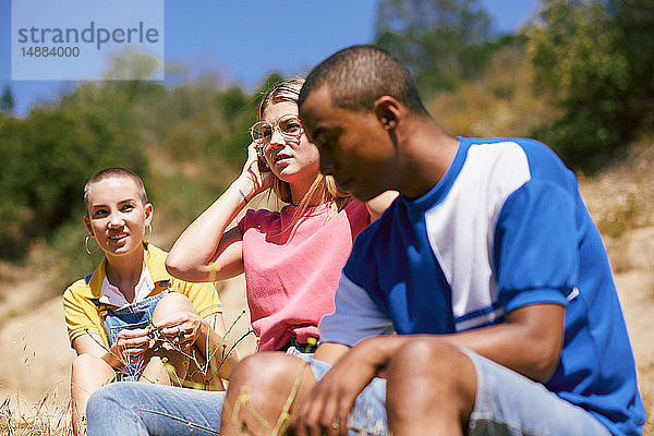 Drei junge erwachsene Freunde sitzen am Feldweg,  Los Angeles,  Kalifornien,  USA