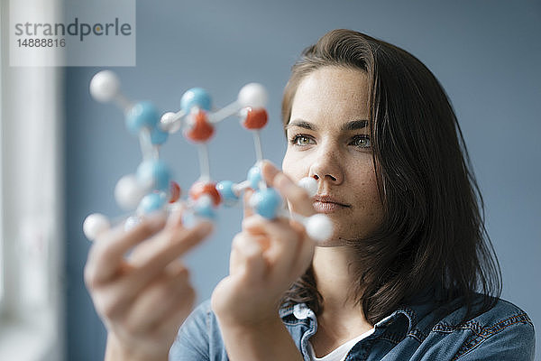 Weibliche Wissenschaftlerin untersucht Molekülmodell,  sucht nach Lösungen