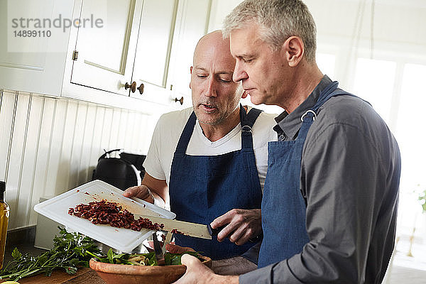 Kahler,  reifer Mann hilft Freund beim Kochen zu Hause
