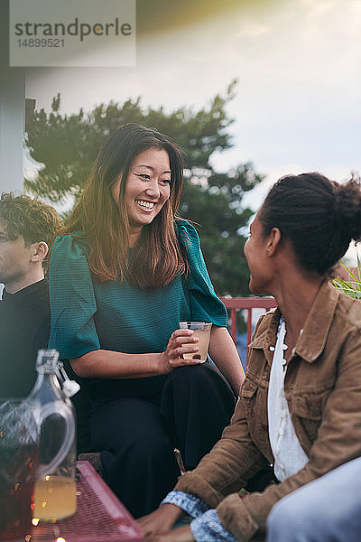 Fröhliche Freundinnen unterhalten sich während einer Party auf der Terrasse