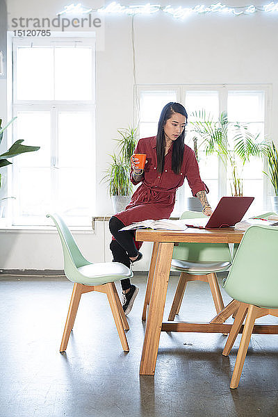 Frau benutzt Laptop auf Tisch im Büro