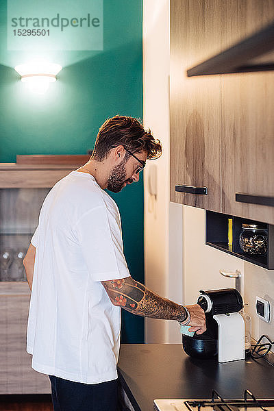 Mittelgroßer Erwachsener,  der Kaffee aus der Kaffeemaschine auf die Küchentheke gießt