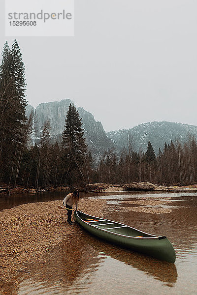 Junge Kanufahrerin beim Ziehen eines Kanus vom Fluss,  Yosemite Village,  Kalifornien,  USA