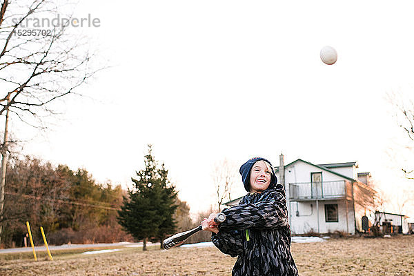 Junge schlägt Baseball auf ländlichem Feld,  Aktion