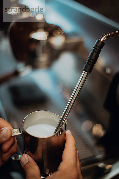 Barista erwärmt Milchkännchen auf der Kaffeemaschine im Café,  Nahaufnahme