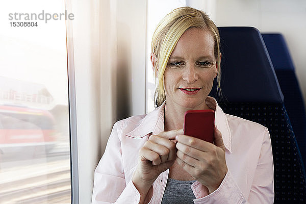 Frau benutzt Smartphone in einem Zug