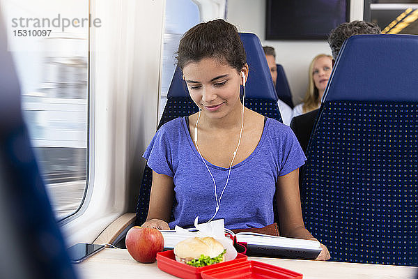 Teenagerin,  die allein mit dem Zug reist,  Musik hört,  einen Imbiss isst