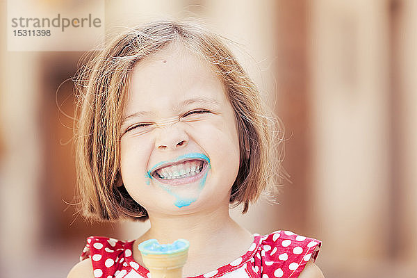 Ein glückliches Mädchen isst ein blaues Eis