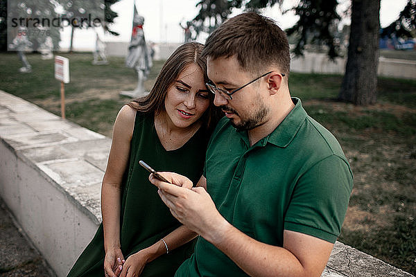 Ehepaar betrachtet Smartphone im Freien