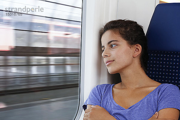 Allein im Zug reisendes Mädchen,  das aus dem Fenster schaut