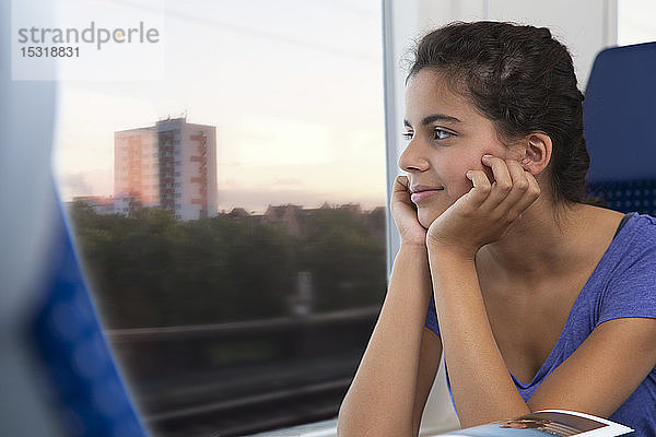 Allein im Zug reisendes Mädchen,  das aus dem Fenster schaut