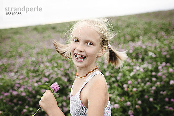 Lachendes Mädchen hält Kleeblumen