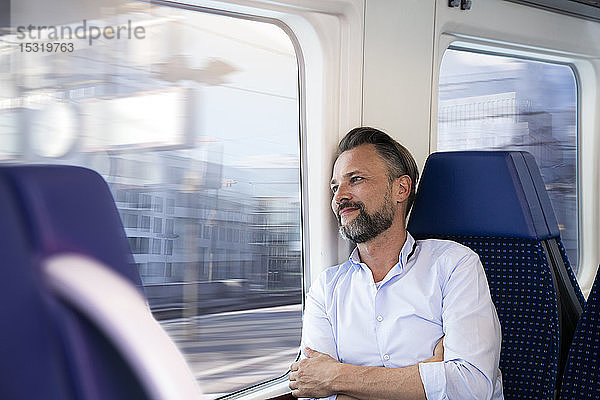 Ein reifer Mann sitzt in einem Zug und schaut aus dem Fenster