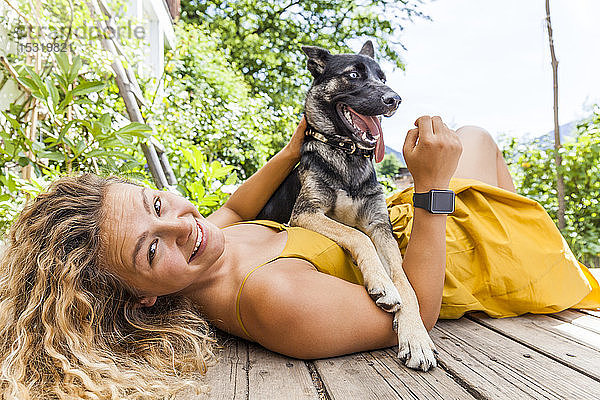 Husky-Schäferhund-Mischlingshund und sein Frauchen auf einem Holzbrett liegend