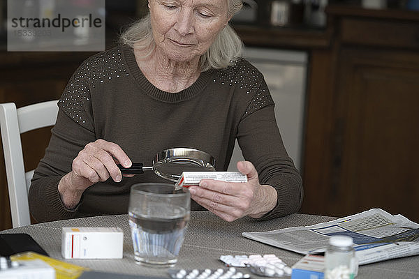 Ältere Frau liest das Etikett einer Pillenschachtel