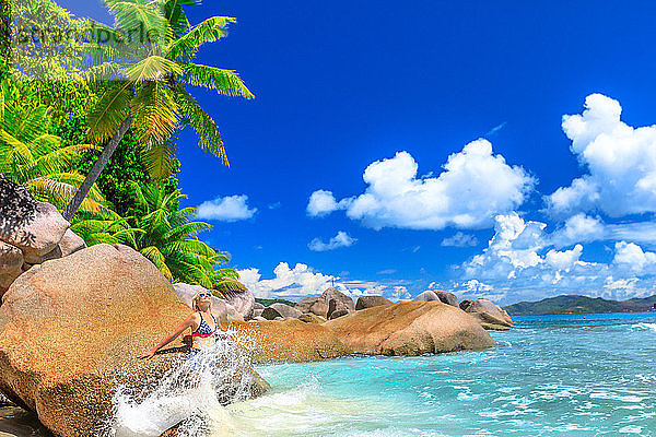 Touristin in plätschernder Welle auf der Insel Felicite,  dahinter Felsen und Palmen,  La Digue,  Seychellen,  Indischer Ozean,  Afrika
