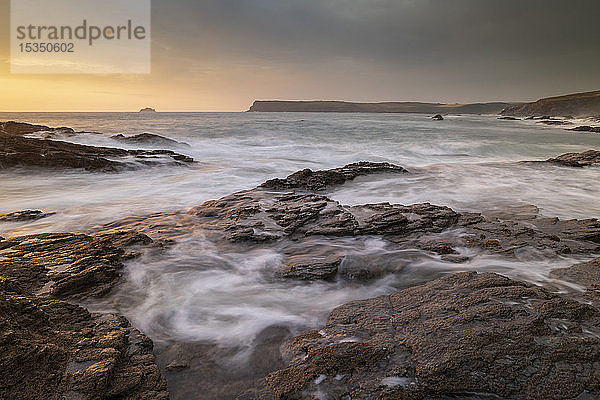 Wellen wirbeln über Felsvorsprünge bei Sonnenuntergang an der Küste von North Cornwall,  Cornwall,  England,  Vereinigtes Königreich,  Europa