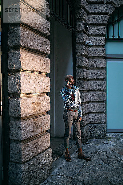 Stilvoller Mann benutzt Handy nach Gebäude der Epoche,  Mailand,  Italien