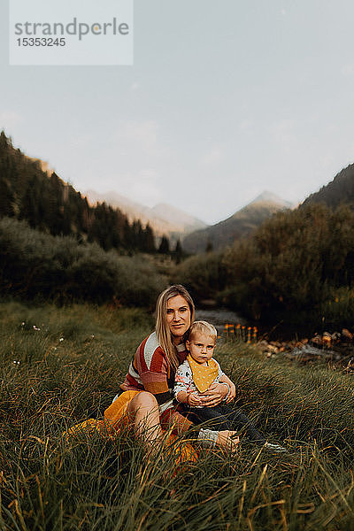 Weibliches Kleinkind sitzt auf dem Schoss der Mutter am ländlichen Fluss,  Porträt,  Mineral King,  Kalifornien,  USA