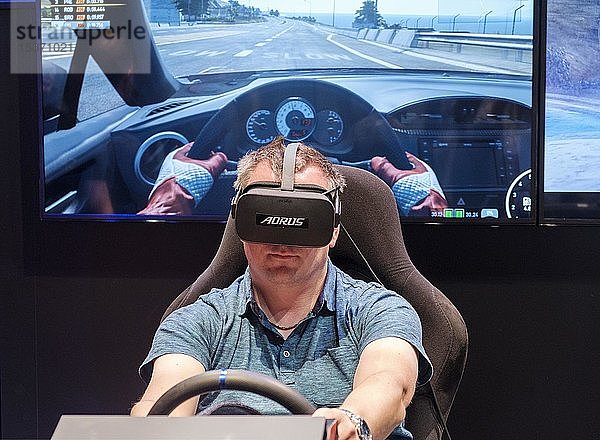 Besucher trägt eine Virtual-Reality-Brille in einem Fahrsimulator für Autorennen auf der gamescom,  der weltweit größten Messe für Video- und Computerspiele in Köln,  Deutschland,  Europa