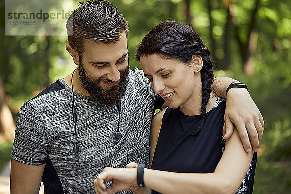 Glückliches sportliches Paar beim Prüfen der Smartwatch