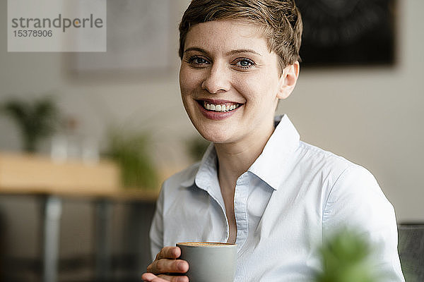 Porträt einer glücklichen Geschäftsfrau mit einer Tasse Kaffee