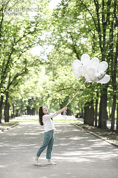 Glückliche Frau mit Luftballons in einem Park