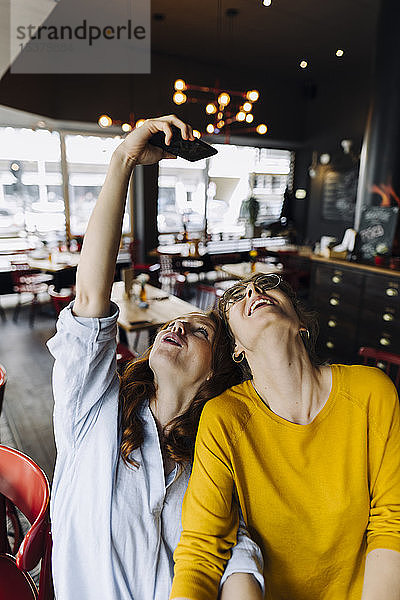 Zwei glückliche Freundinnen beim Selfie in einem Restaurant