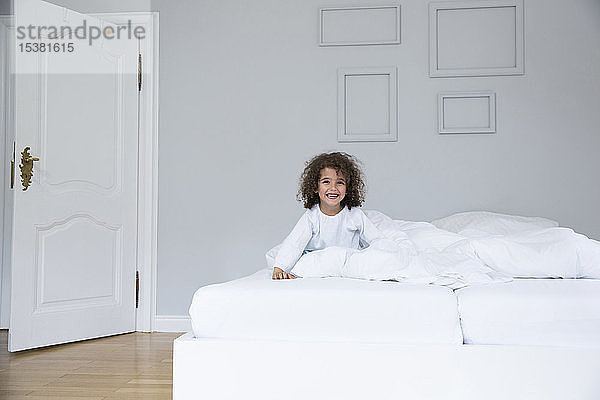 Porträt eines süßen,  glücklichen Jungen im Bett