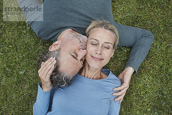 Draufsicht auf ein liebevolles reifes Paar,  das im Gras liegt