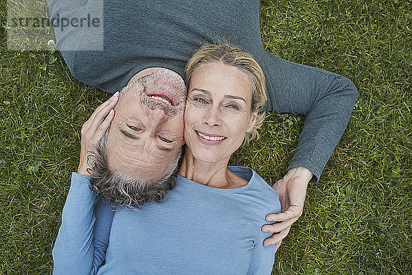 Draufsicht auf ein glückliches,  reifes Paar,  das im Gras liegt