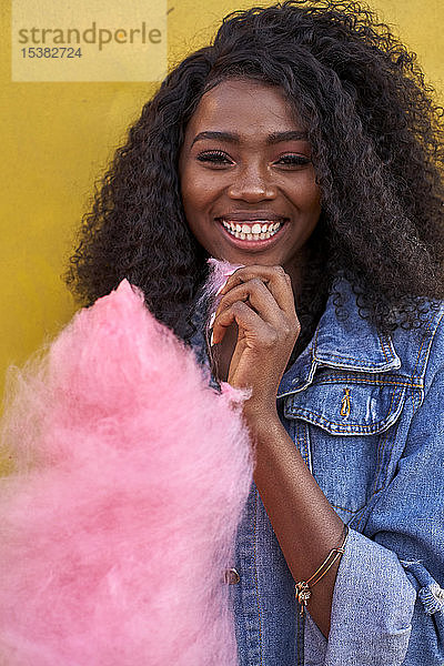 Porträt einer glücklichen jungen Frau mit rosa Zuckerwatte