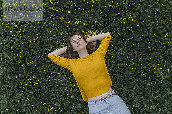 Junge Frau liegt auf einer Blumenwiese