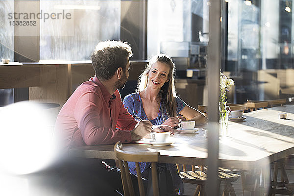 Frau und Mann unterhalten sich am Tisch in einem Cafe