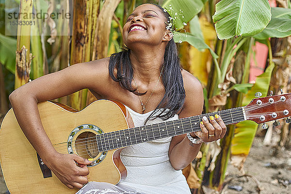 Glückliche Frau spielt Gitarre im Freien