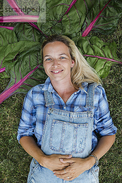 Blonde Frau erntet Gemüse von ihrem Hochbeet in ihrem eigenen Garten