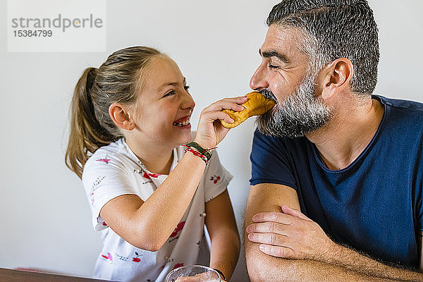 Glückliche Tochter füttert Vater zu Hause