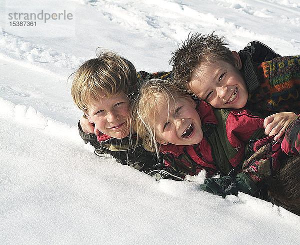 Gruppenbild von drei glücklichen Kindern im Schnee