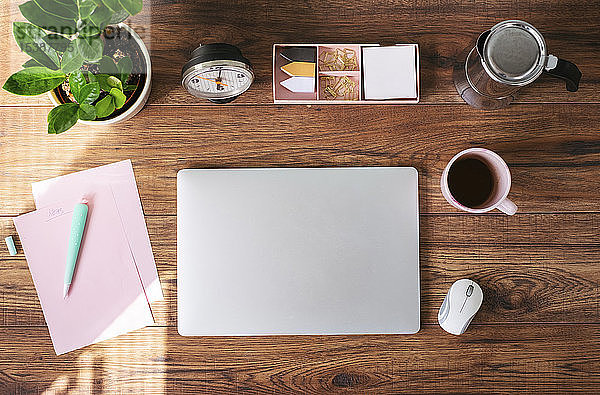 Geschlossener Laptop,  Kaffeetasse und andere Utensilien auf dem Schreibtisch im Heimbüro,  Draufsicht