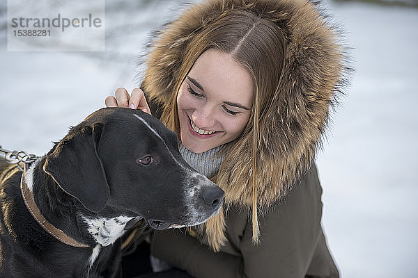 Glückliche junge Frau mit Hund im Winter