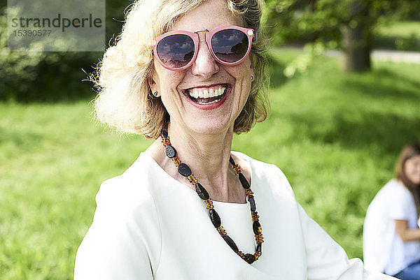 Porträt einer glücklichen älteren Frau mit Sonnenbrille im Park