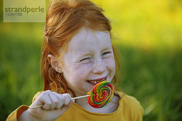 Porträt eines glücklichen Mädchens,  das einen Lolli isst