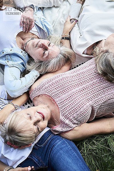 Draufsicht auf eine Gruppe älterer Frauen,  die auf einer Wiese liegen