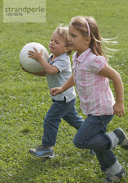 Kinder laufen mit Fussball