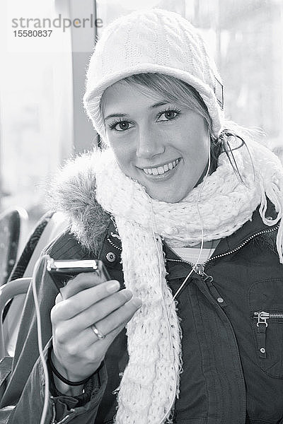 Deutschland,  Augsburg,  Junge Frau hört iPod,  Porträt,  lächelnd