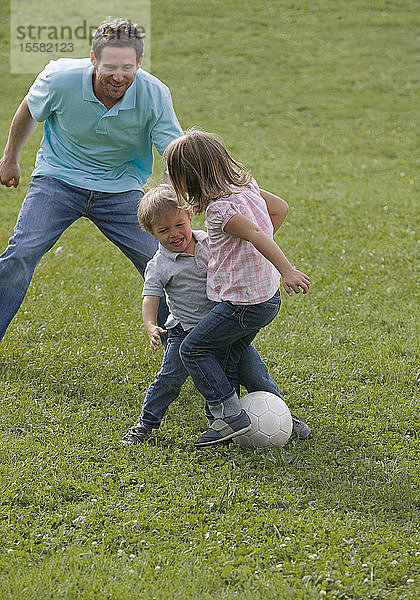 Vater spielt mit Kindern Fussball