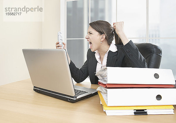 Geschäftsfrau schreit wütend auf Handy im Büro